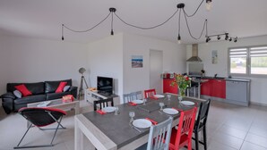 Una sala de estar moderna con comedor, cocina y una paleta de colores en rojo y gris.