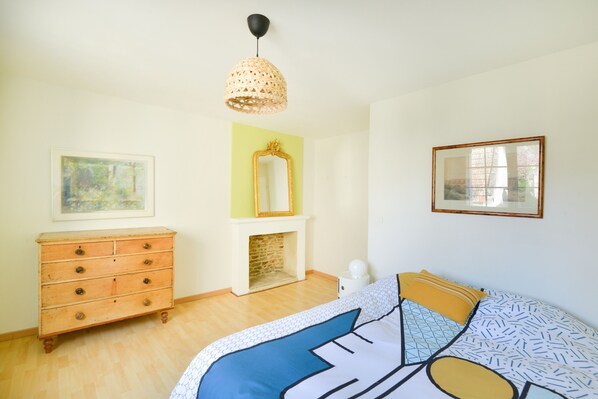 Une chambre à coucher comprenant un lit, une commode, un miroir et un luminaire suspendu.