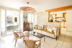 Un salon chaleureux avec un mur en pierre, un canapé, une table basse et des fauteuils en osier.