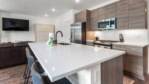A modern kitchen with a central island, stainless steel appliances, and wooden cabinetry. - Serenity in Silverthorne: Luxury Condo Retreat with Mountain Views (Silverthorne)
