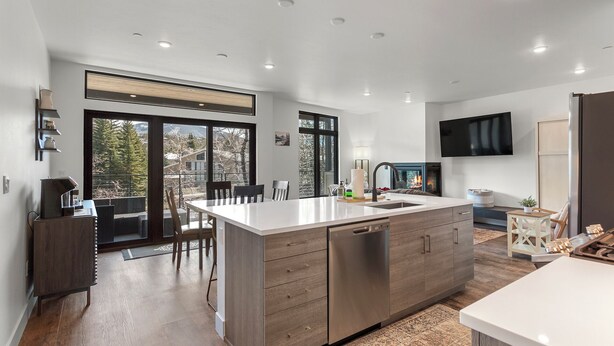 A modern kitchen with a large island, wooden cabinets, and a built-in dishwasher. - Serenity in Silverthorne: Luxury Condo Retreat with Mountain Views (Silverthorne)