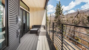 A wooden deck with a metal railing, a sliding glass door, and a bench. - Serenity in Silverthorne: Luxury Condo Retreat with Mountain Views (Silverthorne)