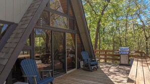 A wooden deck with Adirondack chairs and a grill, overlooking a forested area. - Rustic Fox by Innsbrook Vacations! (Innsbrook)