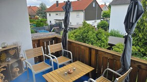 A wooden deck with a table and chairs, a small decorative bowl, and a glass. - Family-friendly apartment to feel good with flair and a large balcony  (Langenzenn)