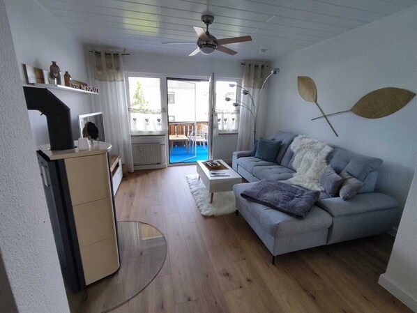 A modern living room with a grey sofa, a coffee table, and a ceiling fan. - Family-friendly apartment to feel good with flair and a large balcony  (Langenzenn)