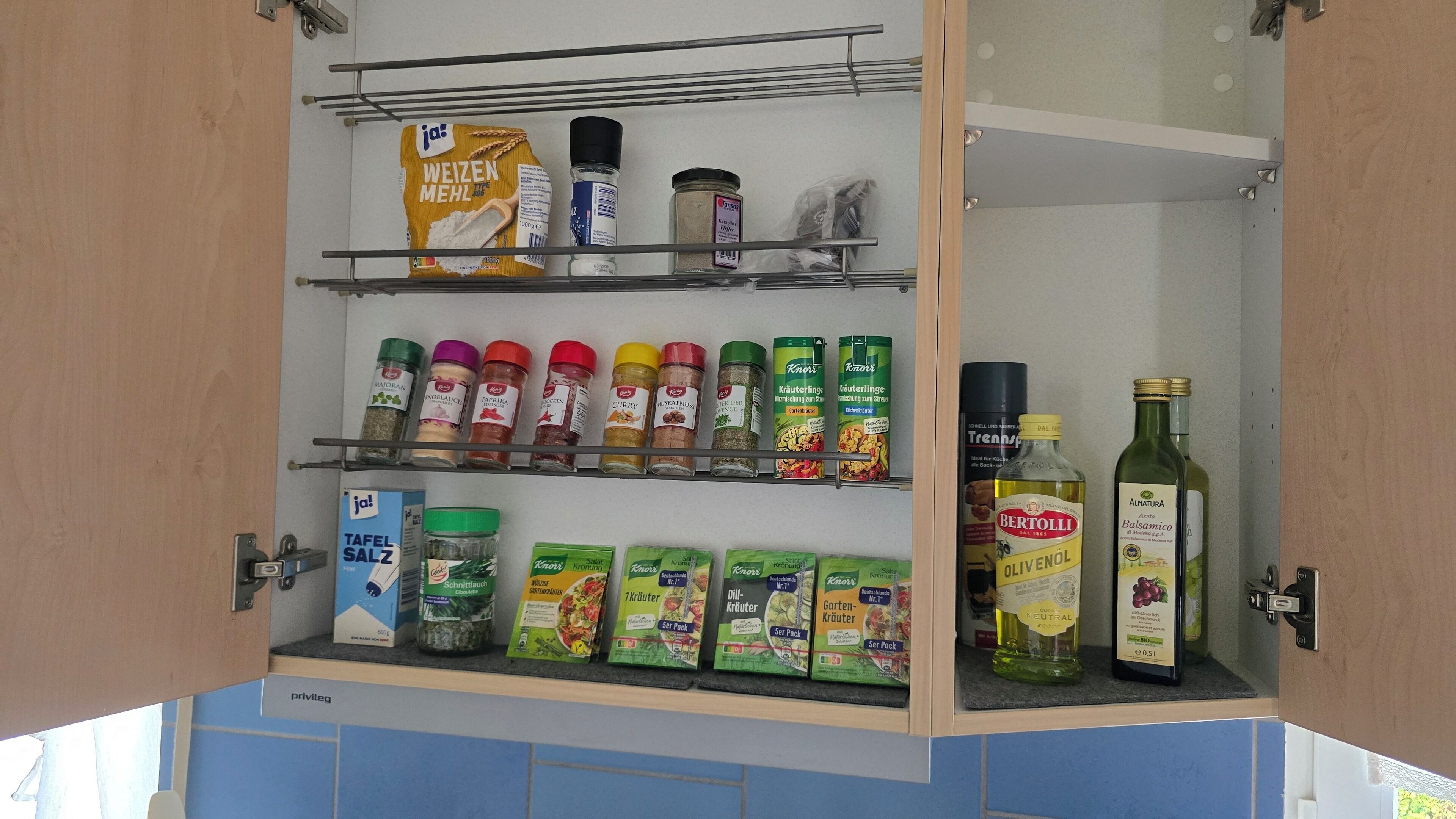 A kitchen pantry with shelves stocked with various food items, including spices, condiments, and packaged goods.