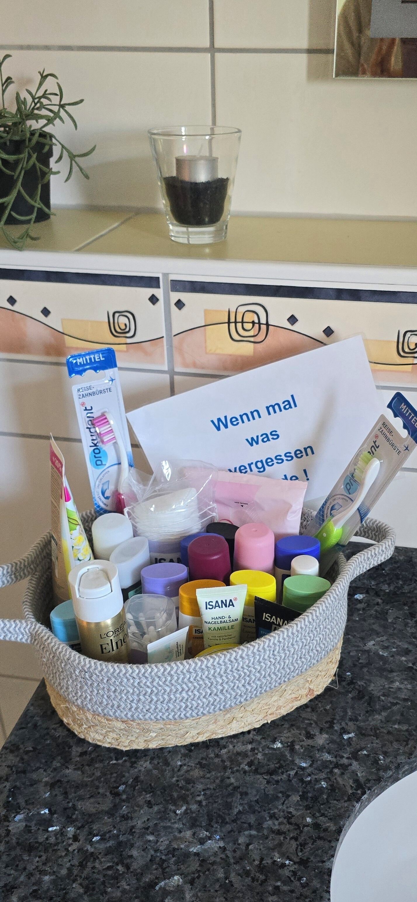 A basket filled with various toiletries and a card on a kitchen counter.