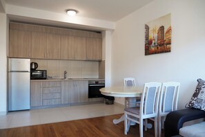 Kitchen features a refrigerator, microwave, and oven, with a dining area and round table for meals.