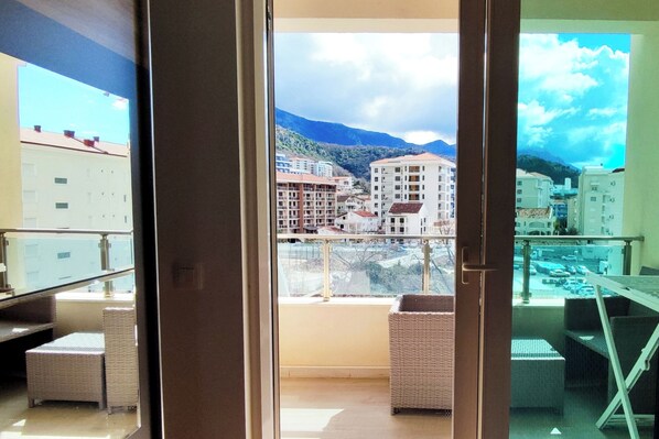 Enjoy the breathtaking view of the town and surrounding mountains from this balcony, complete with comfortable wicker furniture and a secure glass railing.