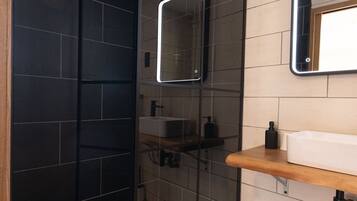 A modern bathroom with a glass-enclosed shower, a wooden vanity, and a mirror above the sink.
