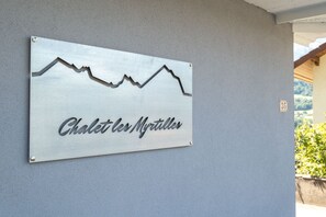 A metal sign with a mountain peak design and the text "Chalet les Myrtilles" on a grey wall. - Chalet les Myrtilles (Venthon)