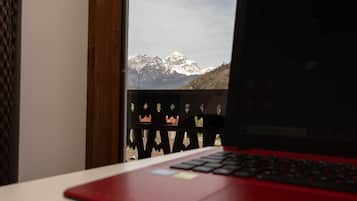 Een laptop op een bureau, met zicht op besneeuwde bergen door een raam.