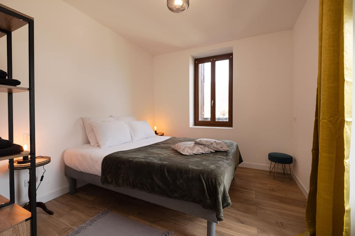 Een slaapkamer met een bed, nachtkastje en een raam.