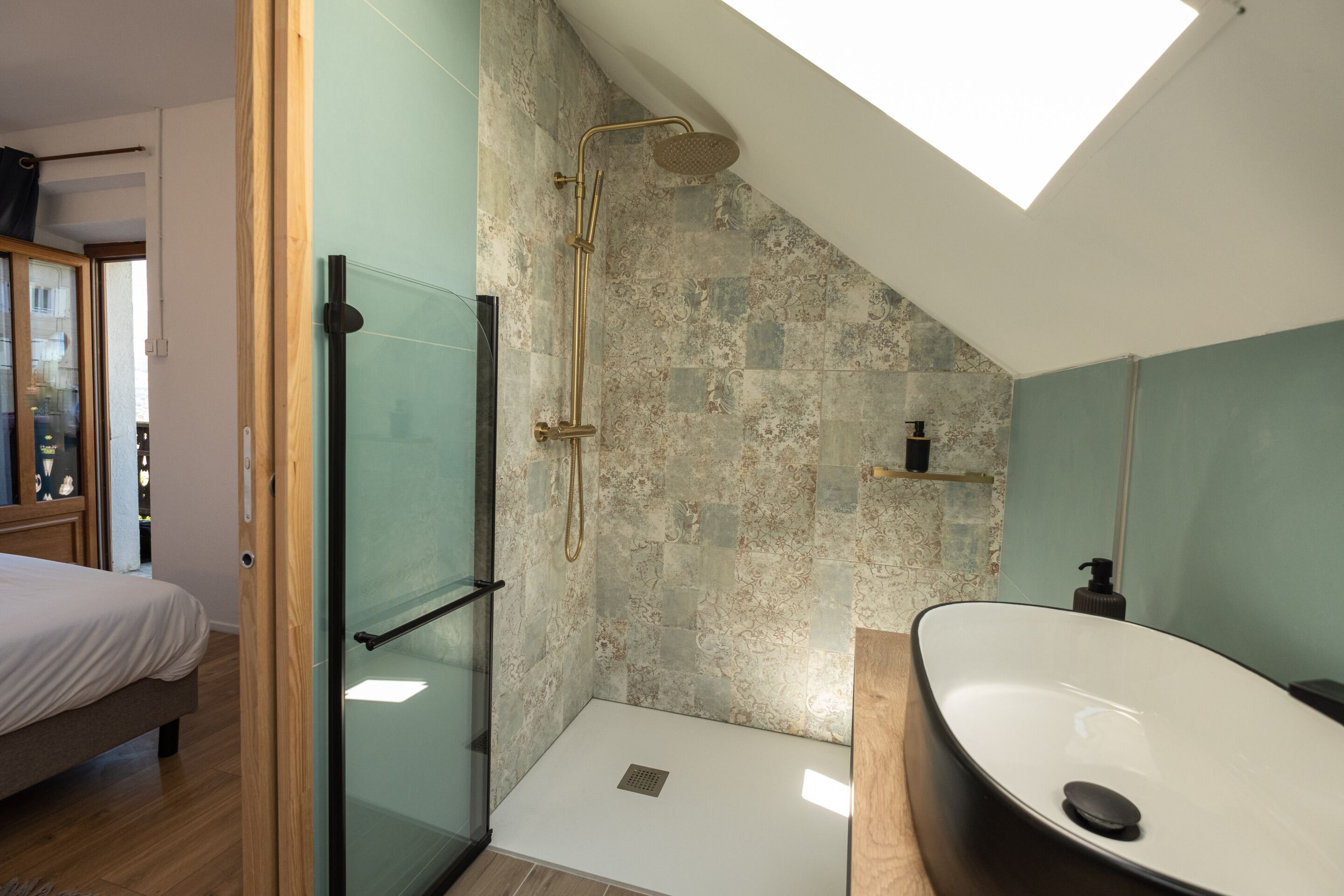 A modern bathroom with a shower, a large sink, and a skylight.