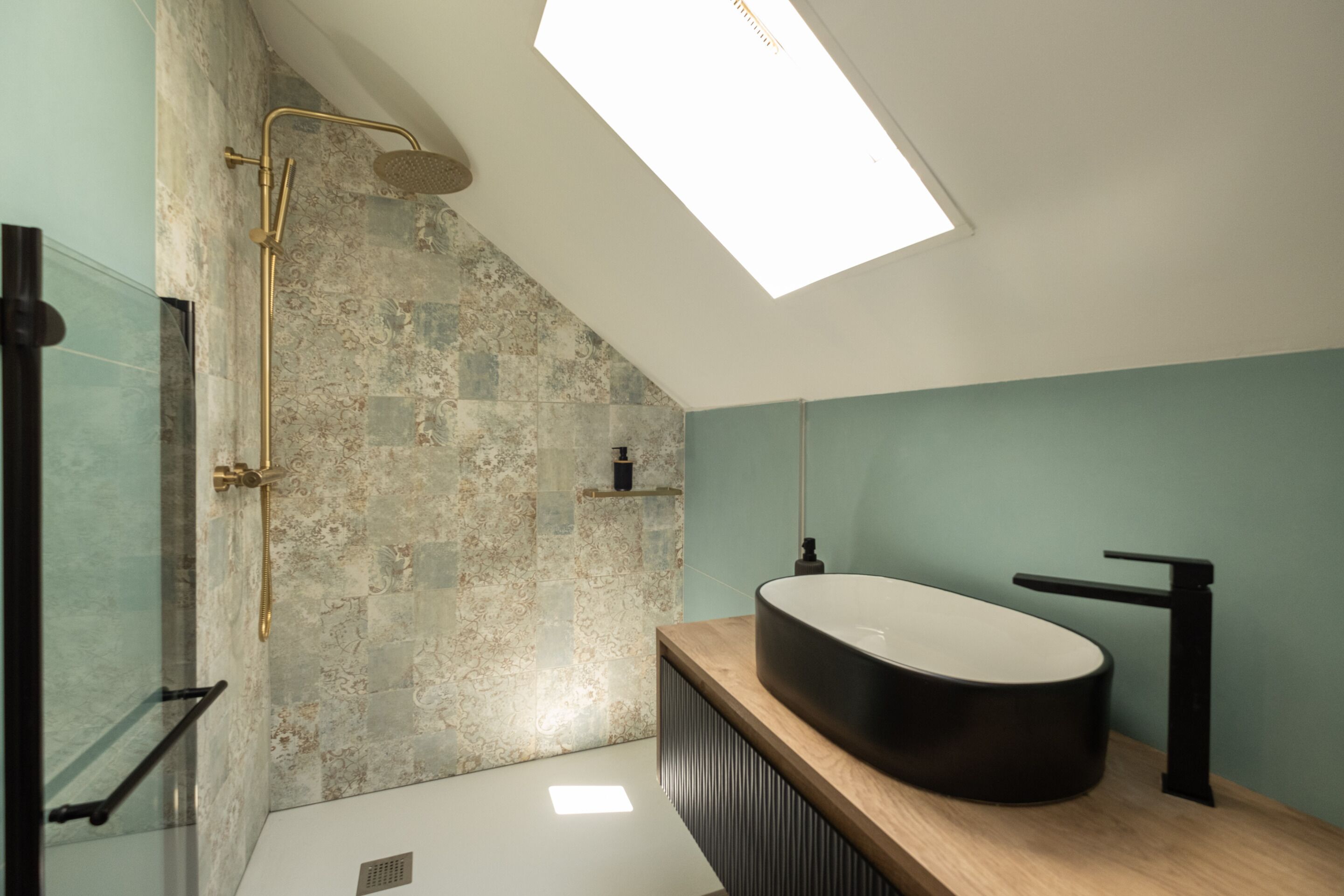 A modern bathroom with a freestanding bathtub, a glass shower enclosure, and a skylight.