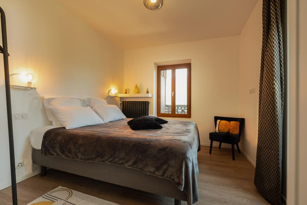 Een slaapkamer met een bed, nachtkastjes, een stoel, een raam en een radiator.