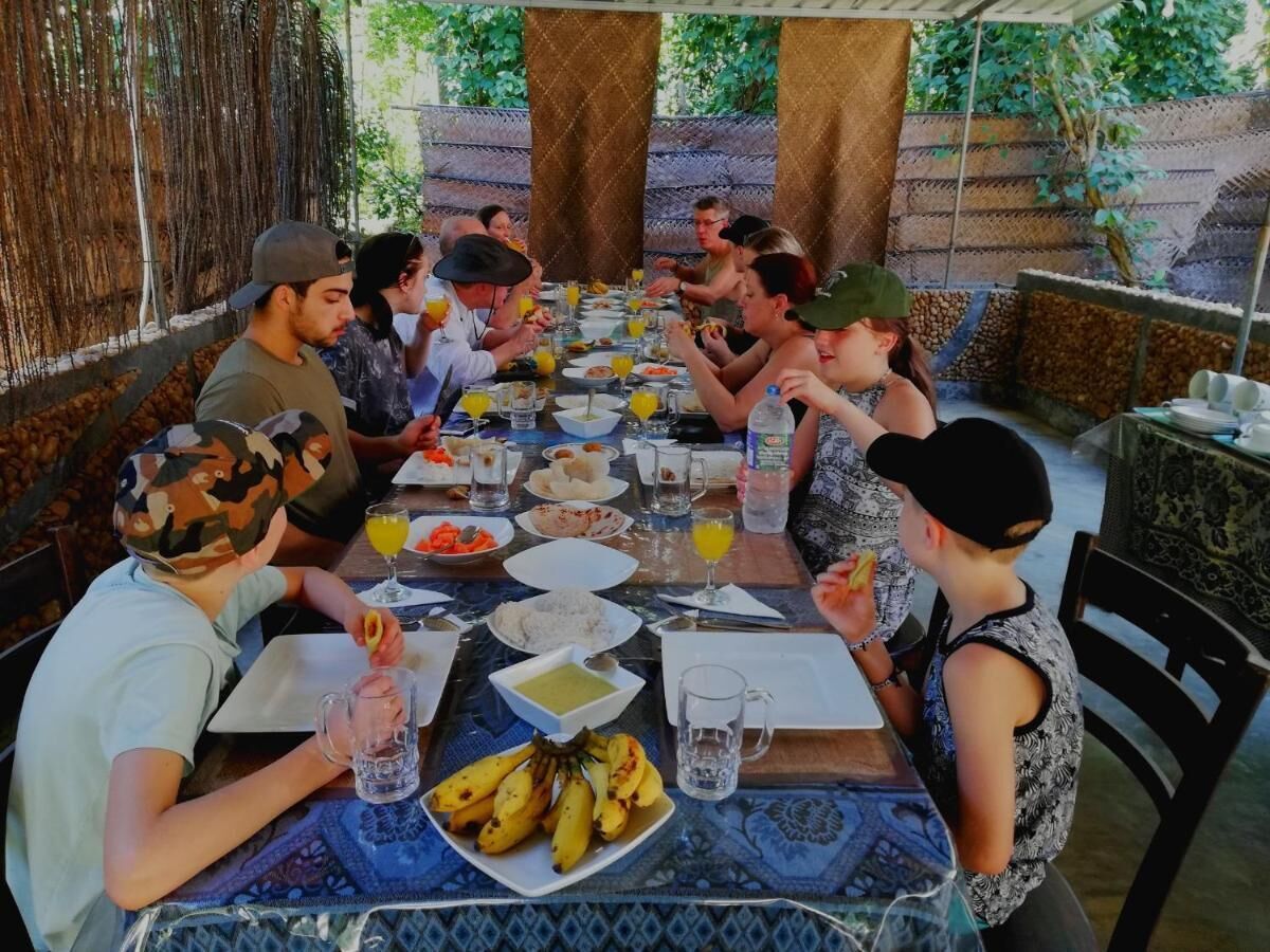 A group of people dining at an outdoor table with a variety of dishes and drinks.