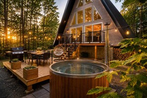 Une maison moderne dotée d’un jacuzzi, d’un espace repas extérieur et d’un escalier menant à une terrasse.