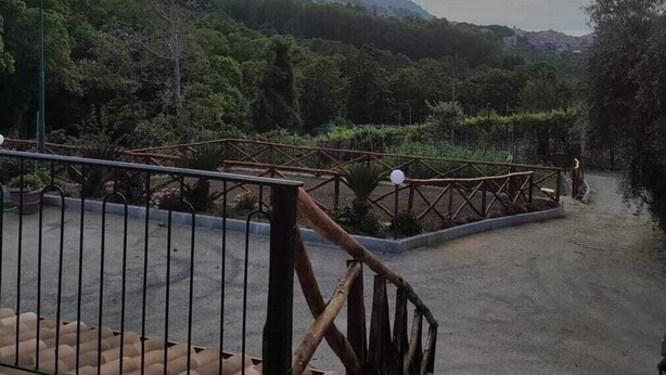 Una escalera conduce a una terraza con vistas a un paisaje montañoso y al atardecer.
