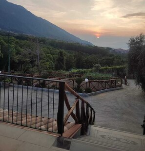 A staircase leading to a terrace with a view of a mountainous landscape and a sunset. - La masseria (Pimonte)