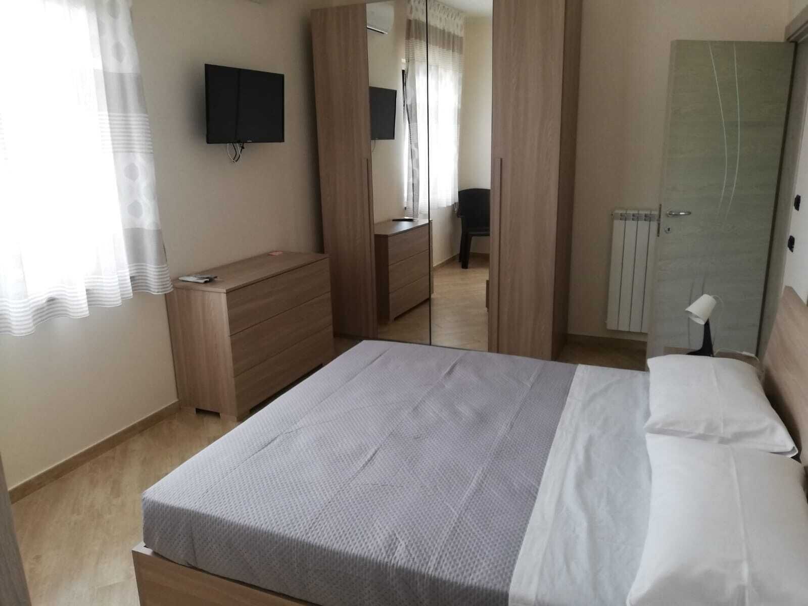 A bedroom with a bed, a dresser, a television, and a wardrobe.