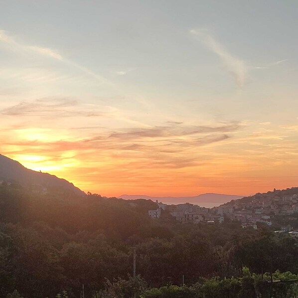 A sunset over a hilly landscape with buildings in the distance. - La masseria (Pimonte)