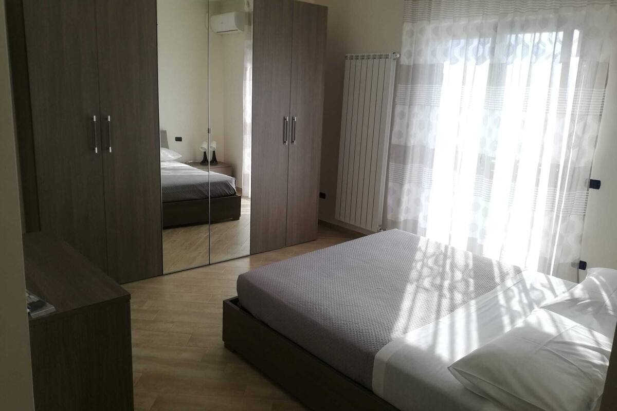 Un dormitorio con una cama grande, un armario y un closet con espejo.