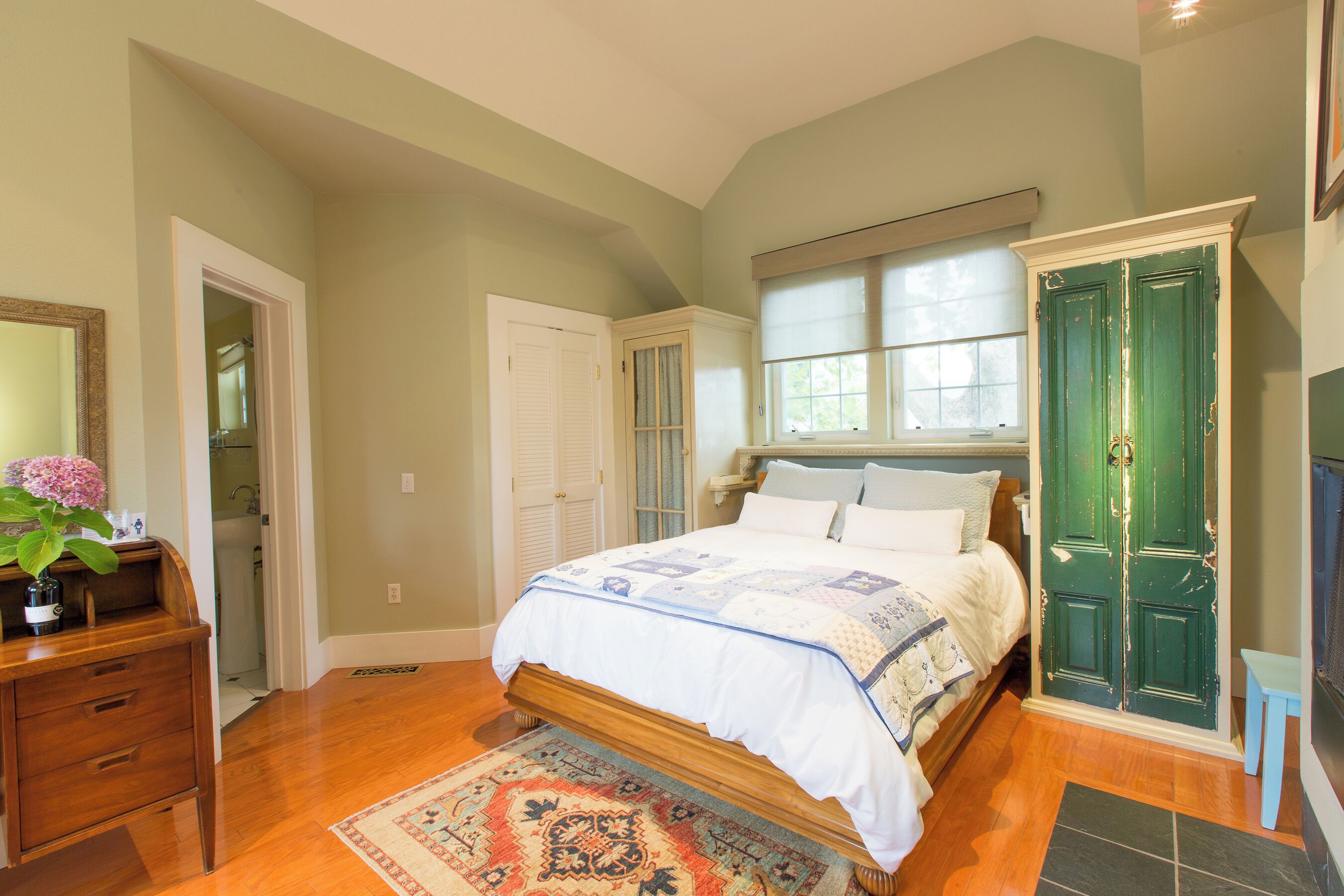 Quarto com cama, penteadeira e porta verde.