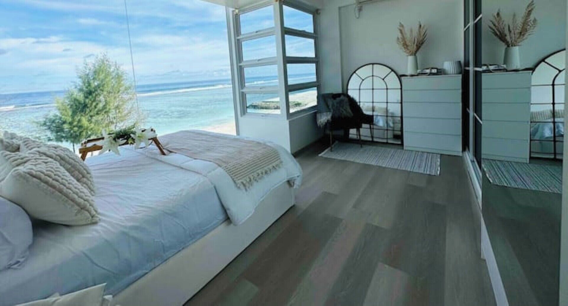 A bedroom with a large bed, a desk, and a view of the ocean.