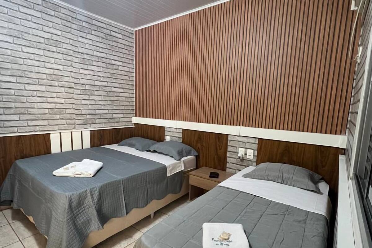 Una habitación con dos camas individuales, un muro con diseño de ladrillo y un cabecero de listones de madera.