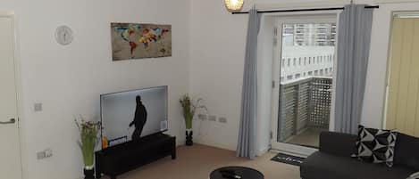 A modern living room with a flat-screen TV, a sofa, a coffee table, and a decorative globe.