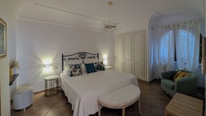 A bedroom with a large bed, a nightstand, a chair, a wardrobe, and a window with curtains. - Perfect destination for families and friends, nestled between seas and mountains (Praiano)