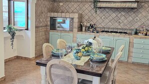 A dining area with a table set for four, a microwave, and a variety of kitchen items on the counter. - Perfect destination for families and friends, nestled between seas and mountains (Praiano)