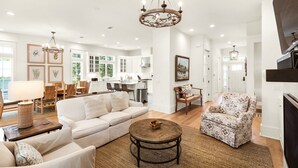 A spacious living room with a white sofa, a patterned armchair, and a wooden coffee table. - SOUTH OF 30A~Walk to beach~4 Bikes!POOL! Sleeps 10 (Santa Rosa Beach)