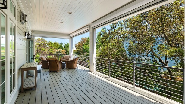 A covered outdoor area with a wooden deck, a table with chairs, and a view of trees and a body of water. - SOUTH OF 30A~Walk to beach~4 Bikes!POOL! Sleeps 10 (Santa Rosa Beach)