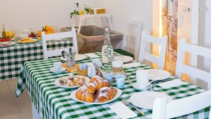 A dining area with a checkered tablecloth, white chairs, and a view of a cityscape through an open door. - Le2Stanze  (Vittoria)