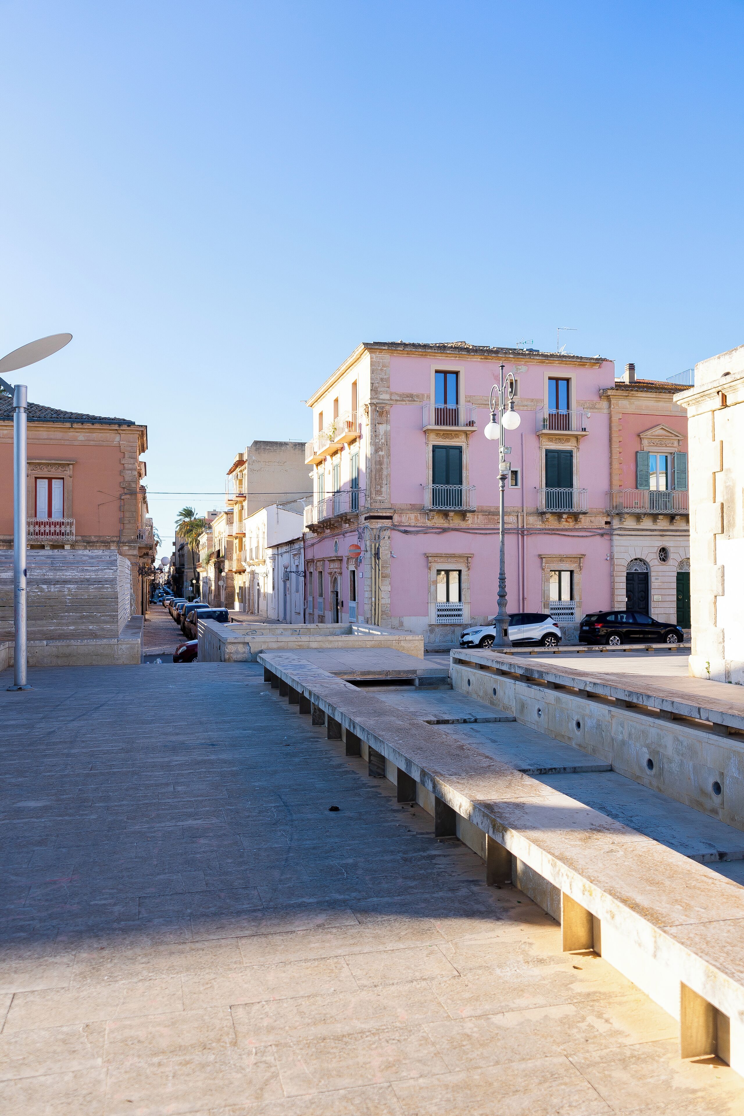 A street with buildings, a bench, and a street lamp.