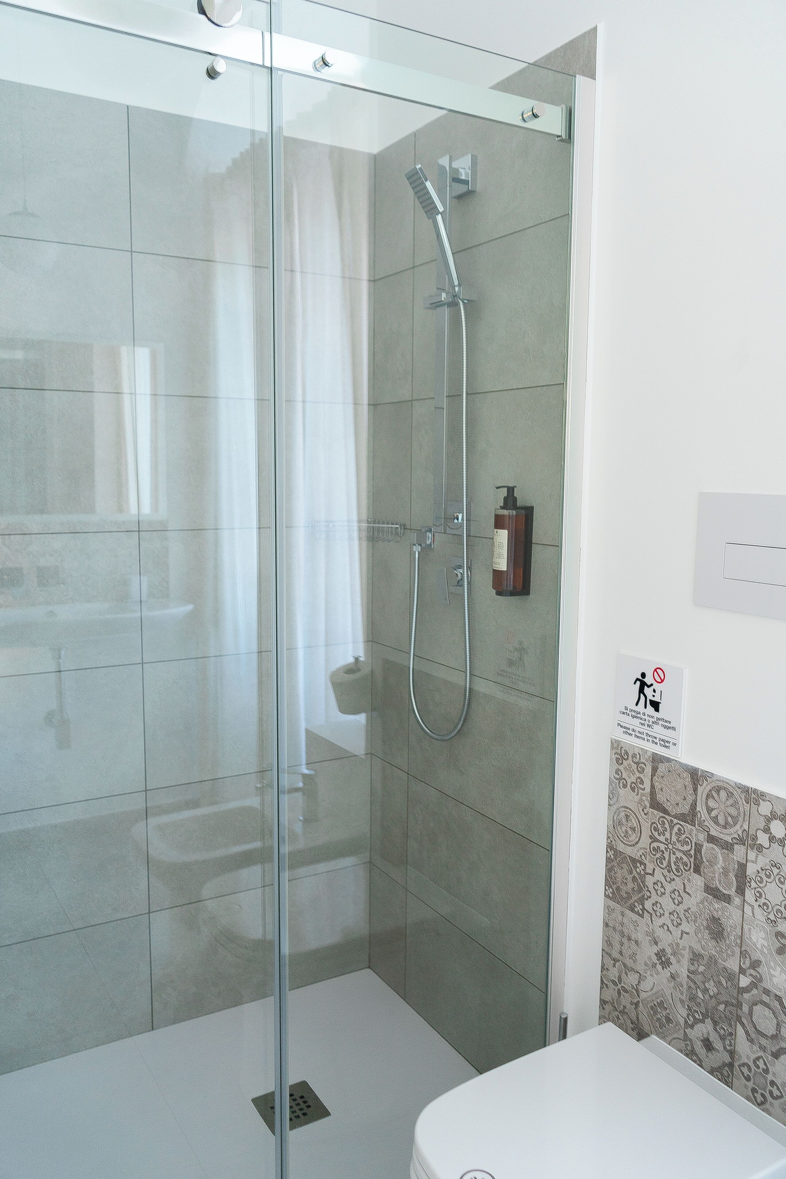 A modern bathroom with a glass-enclosed shower, a toilet, and a sink.