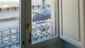 A white door with a glass panel and a metal gate, leading to an outdoor area with a street view. - Le2Stanze  (Vittoria)