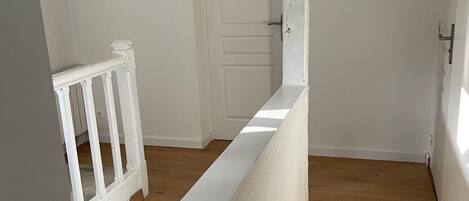 A room with a wooden floor, white walls, and a white door.