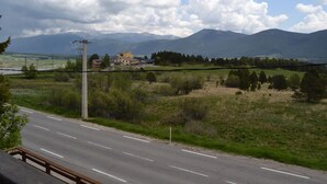 A road with a guardrail, a utility pole, and a building in the distance. - Haut de Chalet Le Bois de Cerf , Animaux Acceptés en Lisière de Foret (Les Angles)