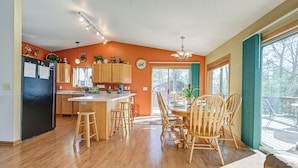 Une cuisine moderne avec des meubles en bois, un réfrigérateur noir et un coin repas comprenant des chaises et une table en bois.