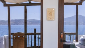 Una habitación con puerta de madera, vista al mar y una placa de madera en la pared.