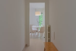 A hallway leading to a dining area with a table and chairs, a lamp, and a radiator.