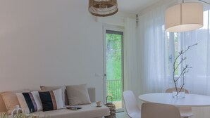 Un salon moderne comprenant un canapé, des fauteuils, une table et un luminaire suspendu.