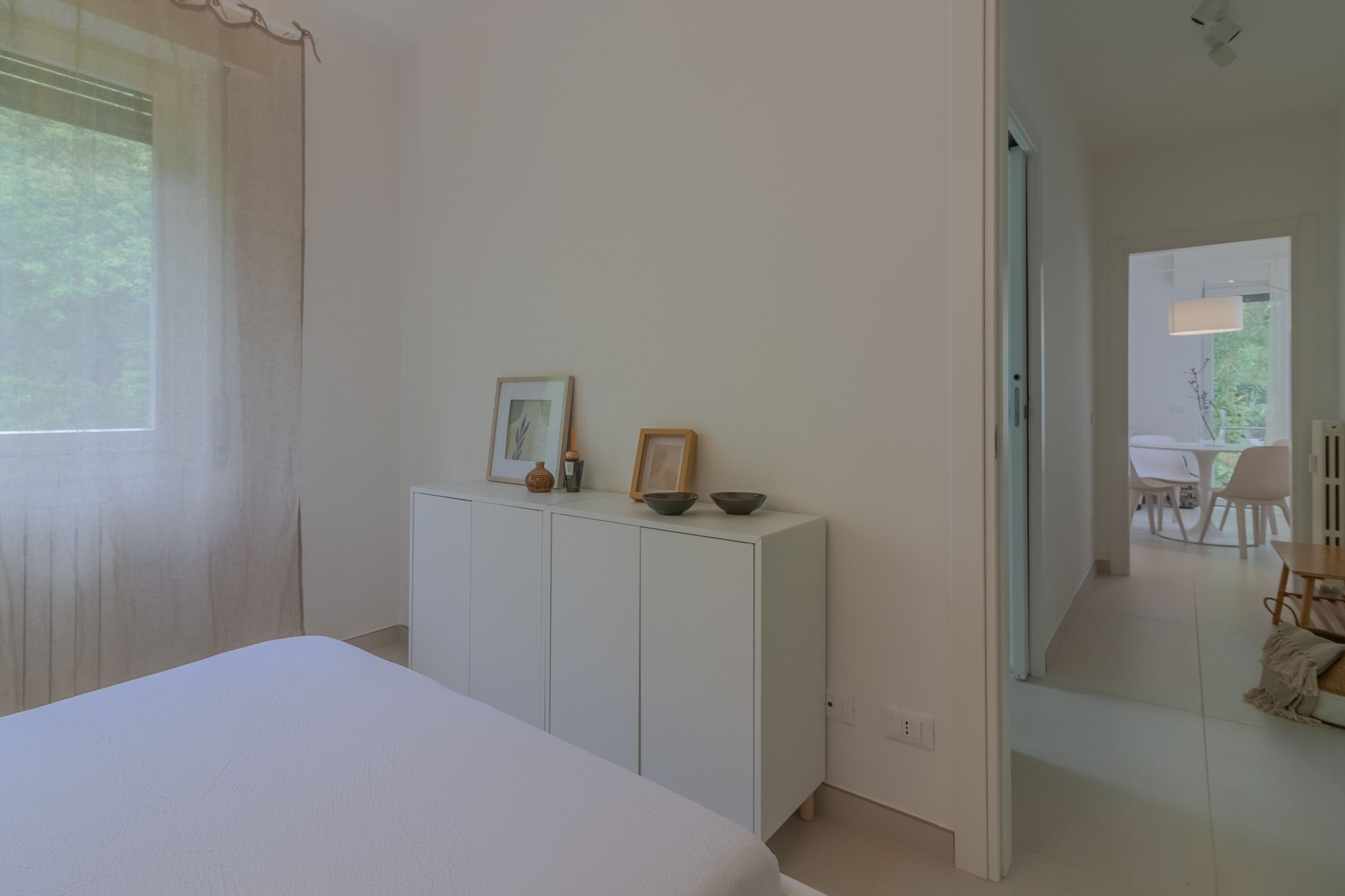 A bedroom with a bed, a white wardrobe, and a small table with decorative items.