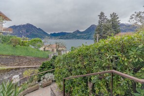 A view of a mountainous landscape with a lake, a building with a red roof, and a stone wall.