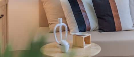 Ein modernes Wohnzimmer mit einer Couch, Kissen, einem kleinen Tisch mit einem weißen Gegenstand und einem Holznachttisch.