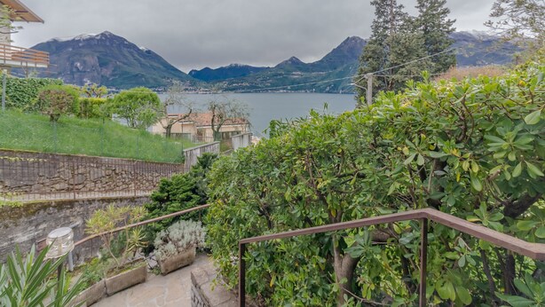 Une vue sur un paysage montagneux avec un lac, un bâtiment doté d’un toit rouge et un mur de pierre.