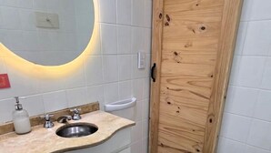 Een badkamer met een houten deur, een wastafel met spiegel en een douchetoilet.